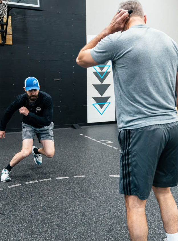 Coach watching an adult member work through an agility drill on the Prime360 training floor