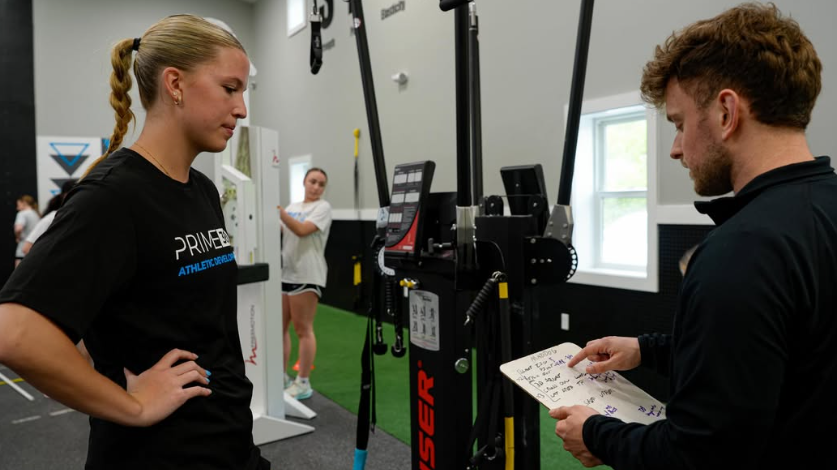 Coach reviewing a session plan on a whiteboard with a Prime360 athlete